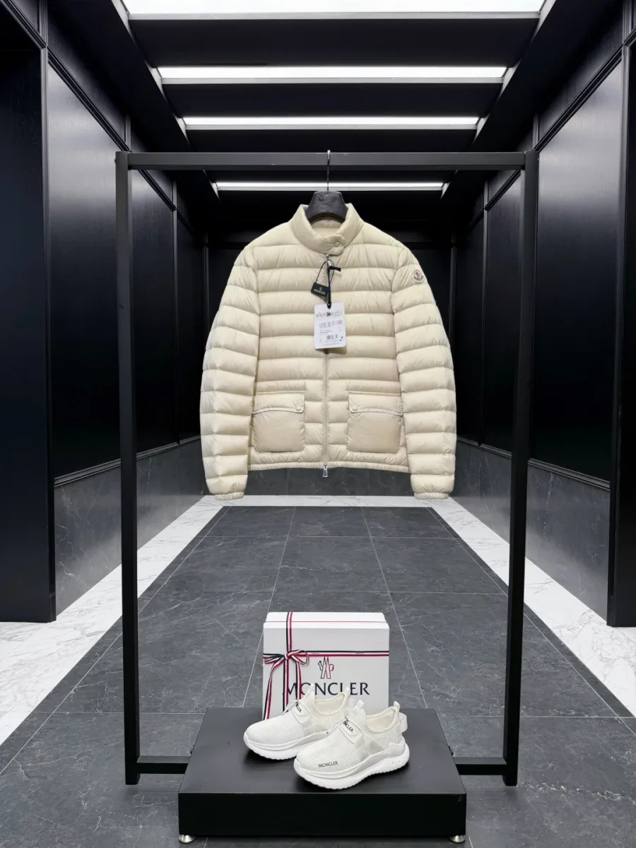 Бежевый пуховик Moncler Lans на вешалке в интерьере бутика, общий вид спереди
