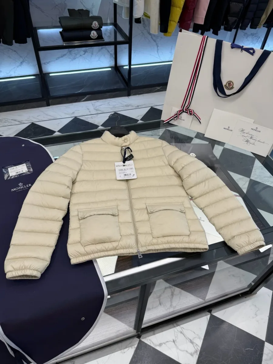 Бежевый пуховик Moncler Lans, разложенный на витрине рядом с упаковкой