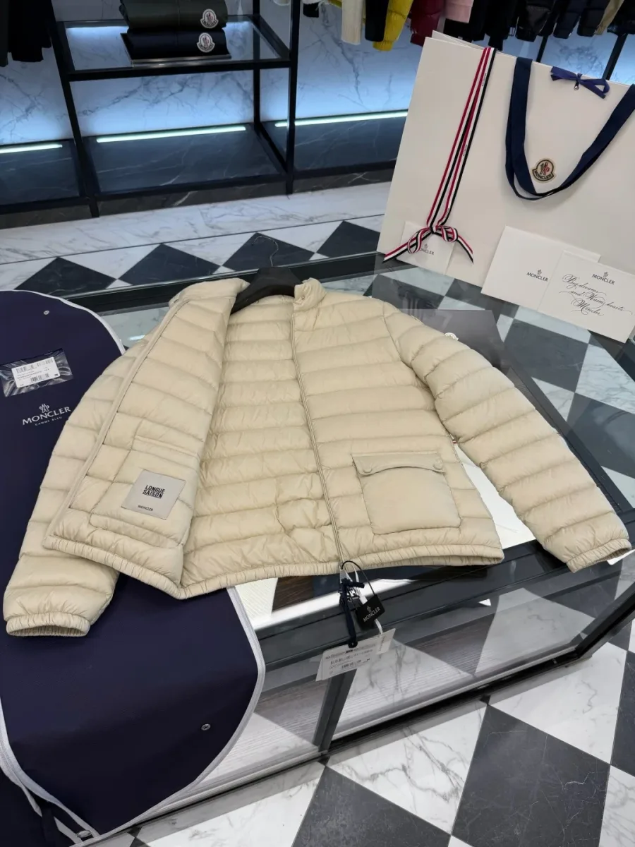 Бежевый пуховик Moncler Lans в расстегнутом виде на стеклянном столе