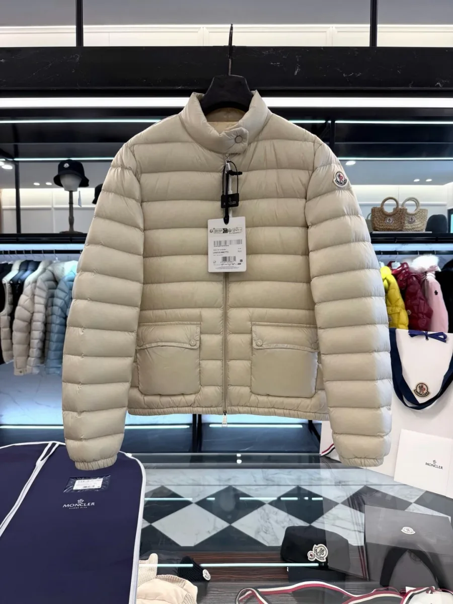 Бежевый пуховик Moncler Lans на черной вешалке над фирменным чехлом