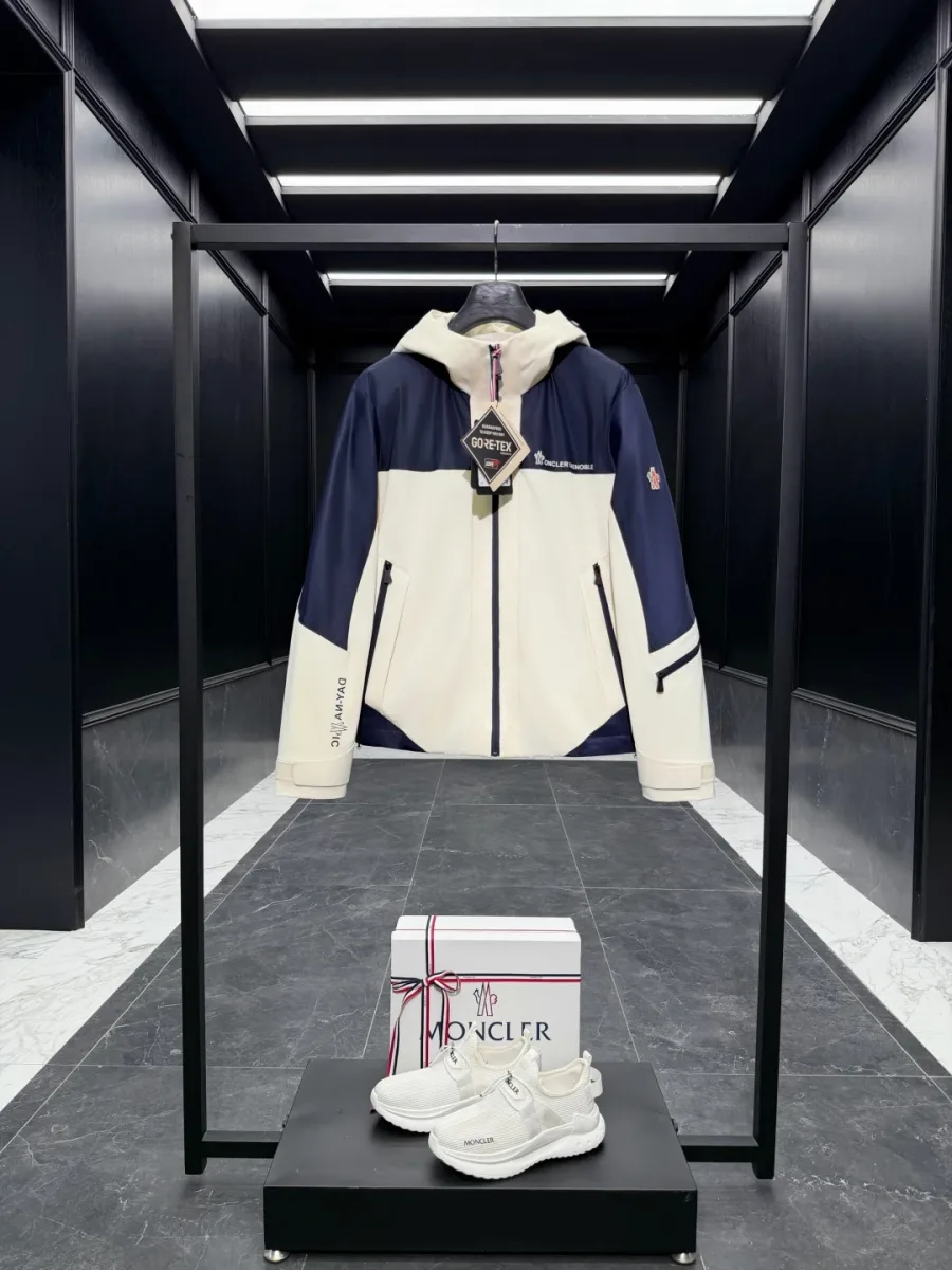 Двухцветный пуховик Moncler Grenoble на вешалке, вид спереди в интерьере