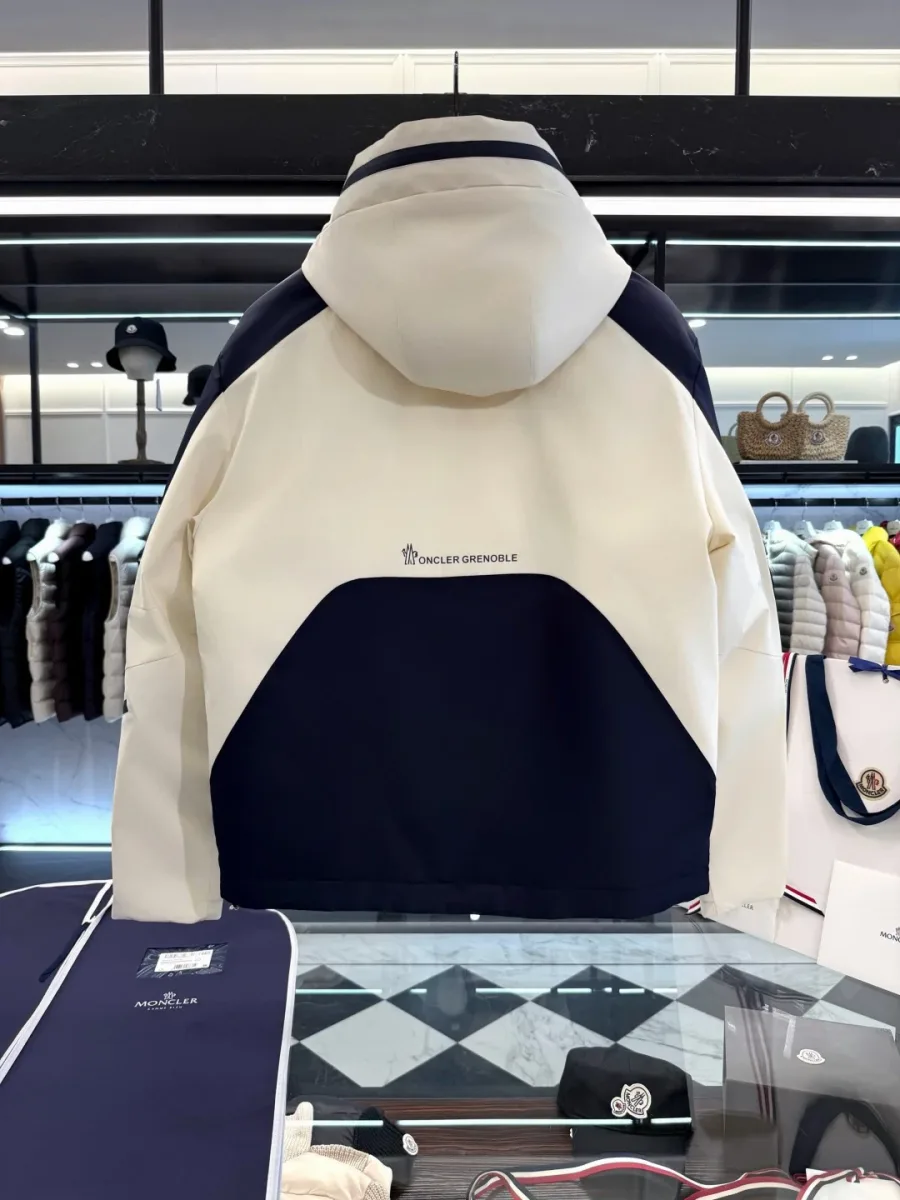 Вид сзади на куртку Moncler Grenoble с синей нижней вставкой на светлом фоне