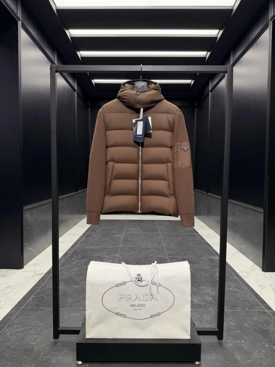 Коричневый комбинированный пуховик Prada на рейле, вид спереди со стёганой грудью и вязаными рукавами