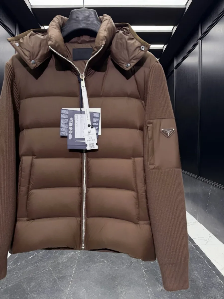 Верхняя часть коричневого пуховика Prada крупным планом: треугольный логотип на рукаве и прорезные карманы