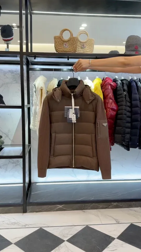 Коричневый комбинированный пуховик Prada на вешалке в интерьере, общий фронтальный ракурс
