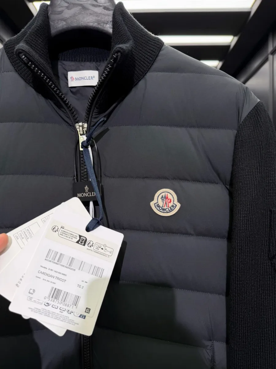 Крупный план ворота-стойки, металлической молнии и нашивки Moncler на чёрной куртке
