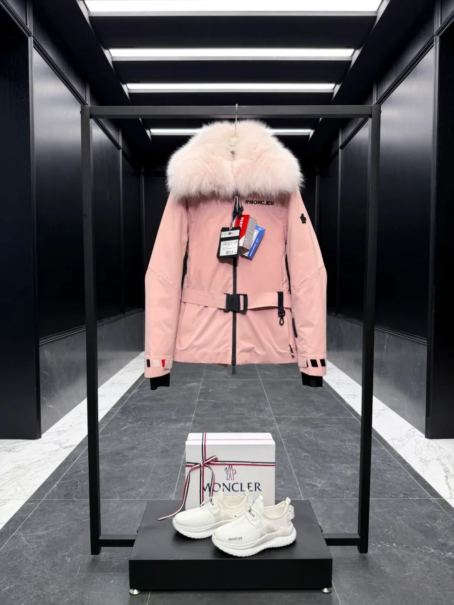 Розовый горнолыжный пуховик Moncler Grenoble с поясом и меховым капюшоном, вид спереди на стойке