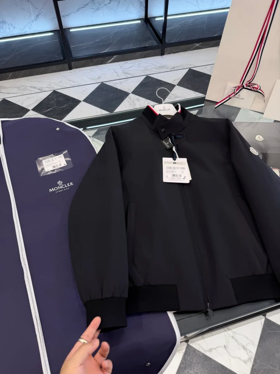 Вид сверху под углом на чёрную куртку-бомбер Moncler Reppe с трикотажной манжетой рукава