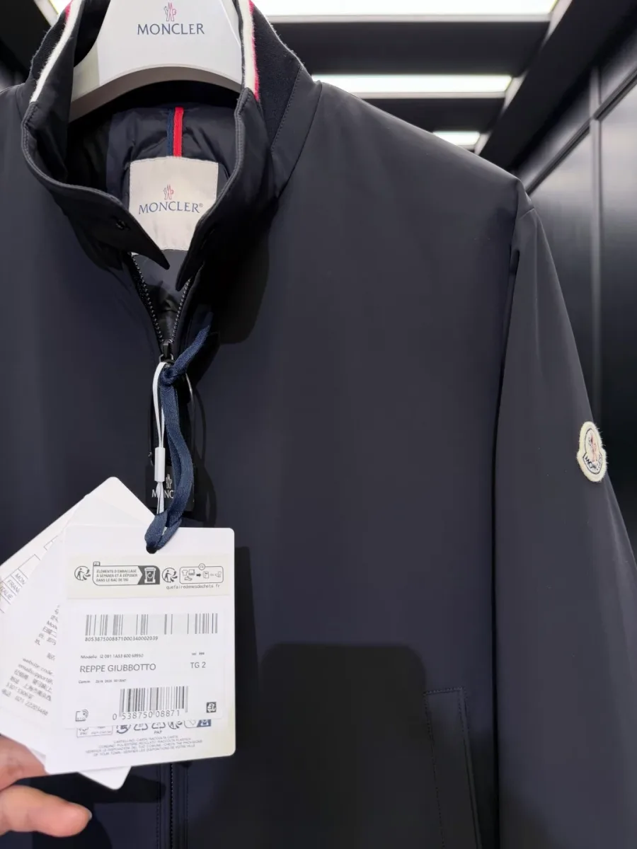Детальный снимок воротника-стойки, внутренней бирки Moncler и картонного ярлыка Reppe Giubbotto