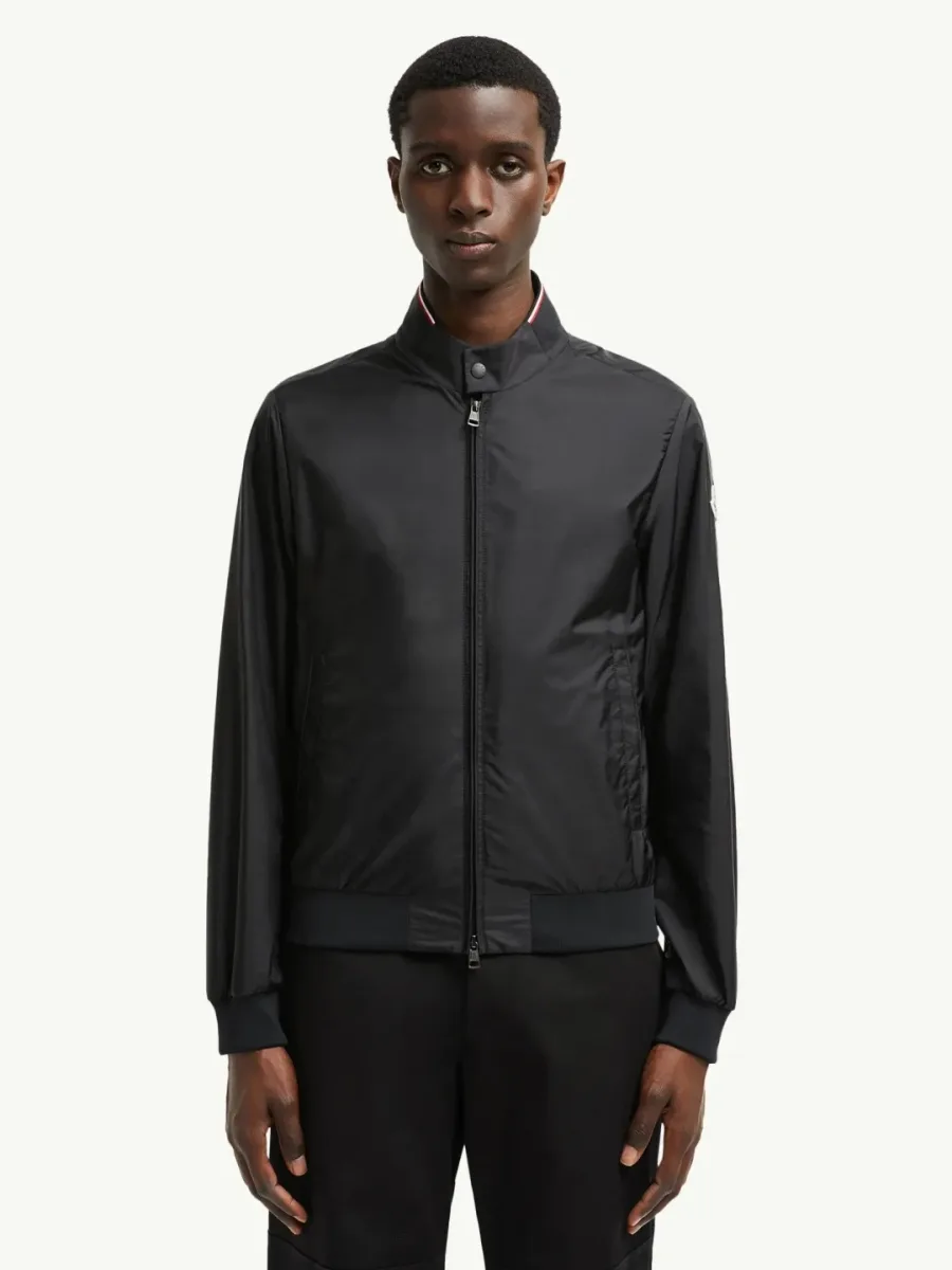 Чёрная куртка-бомбер Moncler Reppe на модели спереди с застёгнутой молнией и триколором