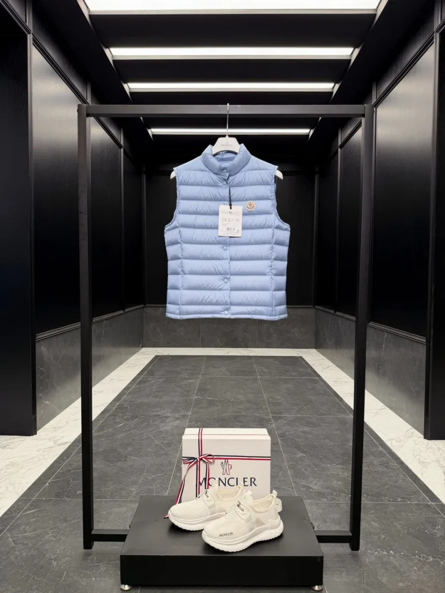 Светло-голубой пуховый жилет Moncler на вешалке в витрине, общий вид спереди