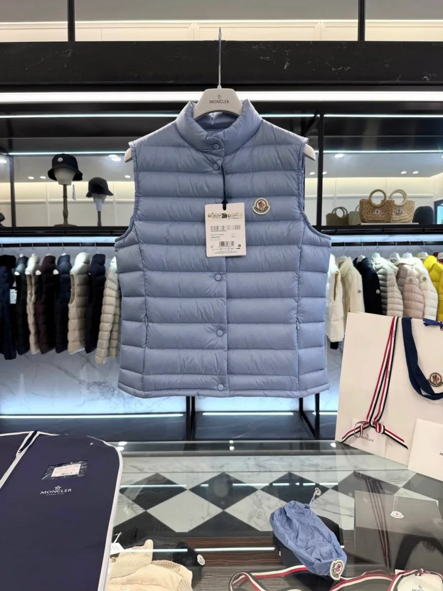 Светло-голубой пуховый жилет Moncler на вешалке в магазине