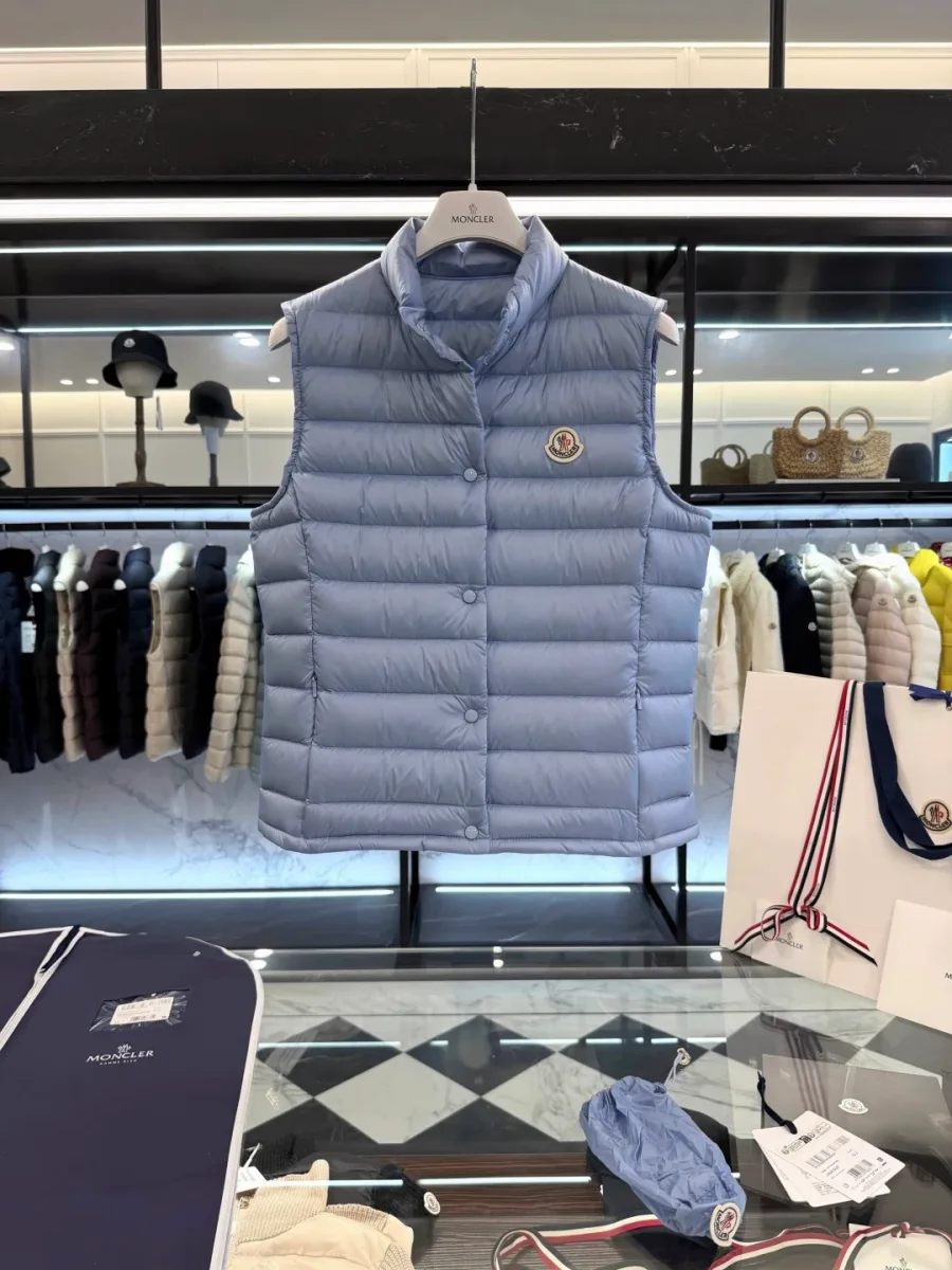 Светло-голубой жилет Moncler с воротником-стойкой на вешалке над стеклянным столом