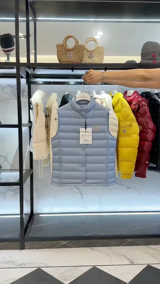 Светло-голубой жилет Moncler на стойке с одеждой в торговом зале