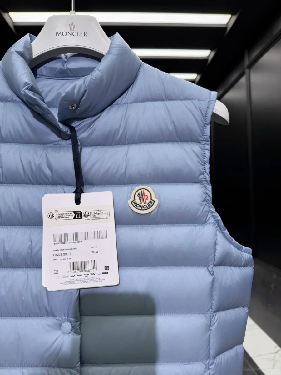 Воротник-стойка, застежка на кнопки и фирменный логотип жилета Moncler Liane