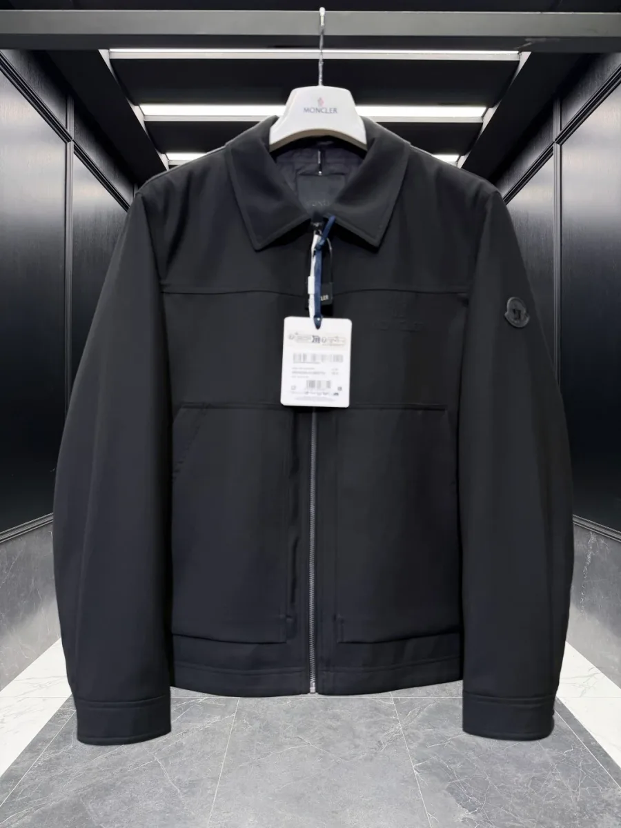 Чёрная куртка Moncler на вешалке крупным планом, прямой ракурс с бирками.