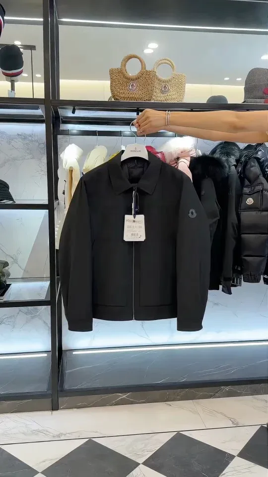 Демонстрация чёрной куртки Moncler в интерьере бутика на вешалке.
