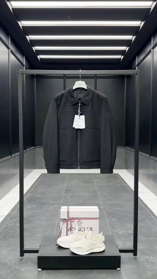 Чёрная куртка Moncler на вешалке в световом тоннеле, вид спереди.