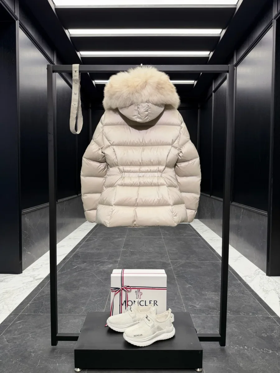 Вид бежевого пуховика Moncler сзади со стегаными полосами и поясом