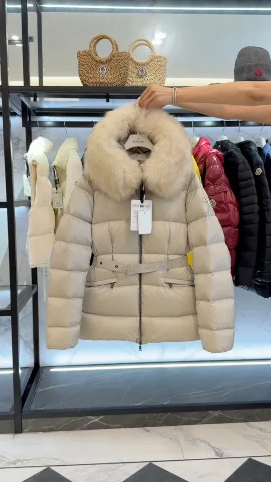 Бежевый пуховик Moncler на вешалке в демонстрационной зоне магазина