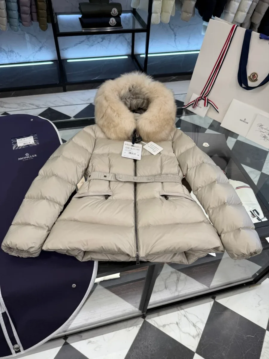 Пуховик Moncler бежевого цвета в разложенном виде на стеклянной витрине