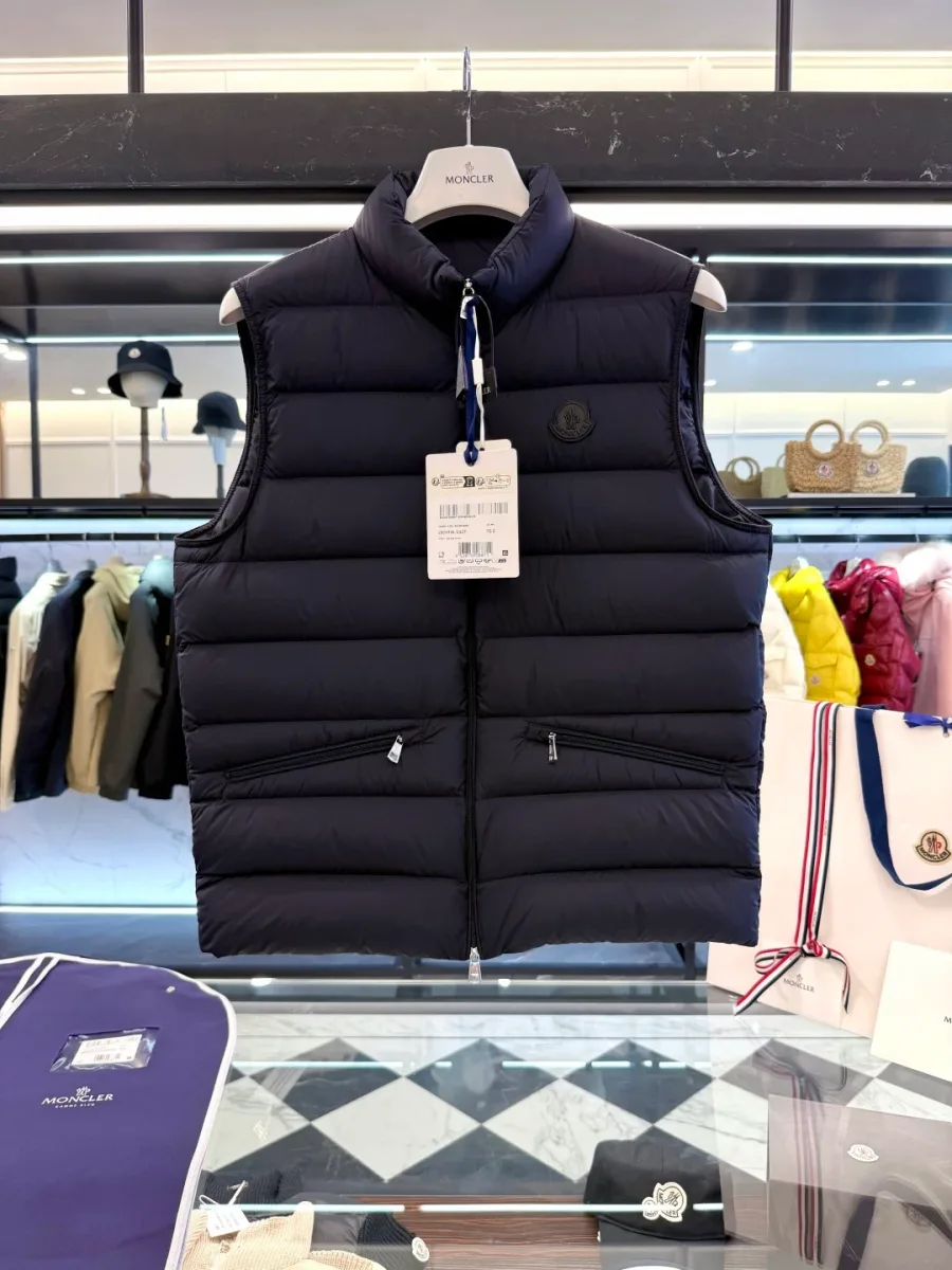 Тёмно-синий жилет Moncler с воротником-стойкой и карманами на молнии на вешалке, вид спереди
