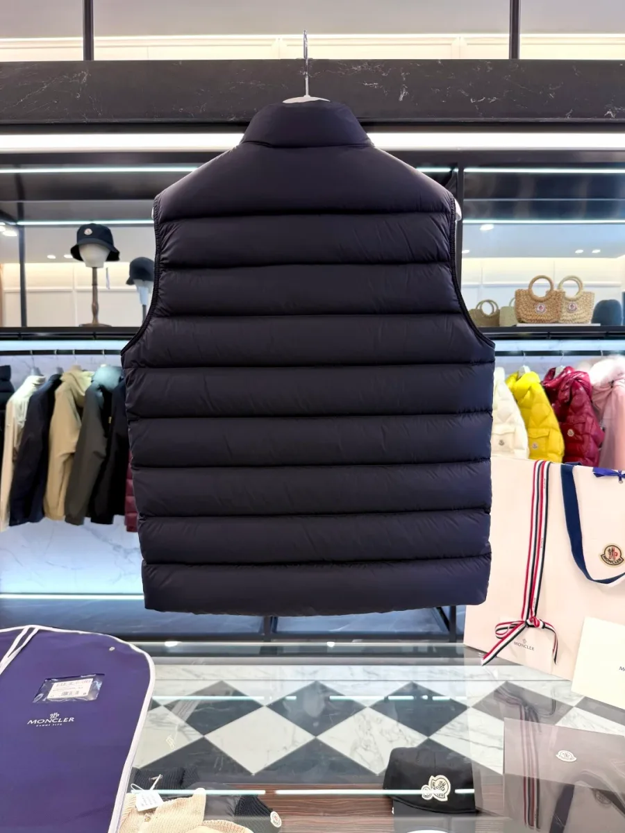 Спинка тёмно-синего жилета Moncler с горизонтальной стёжкой и прямым низом на вешалке вблизи