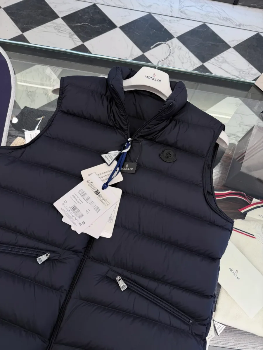 Верхняя часть тёмно-синего жилета Moncler с воротником-стойкой и тёмным патчем, вид сверху