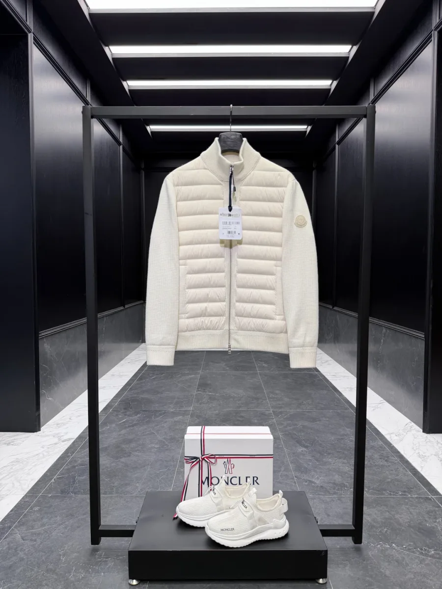 Белый вязаный кардиган Moncler с пуховой стёганой вставкой спереди на вешалке в интерьере