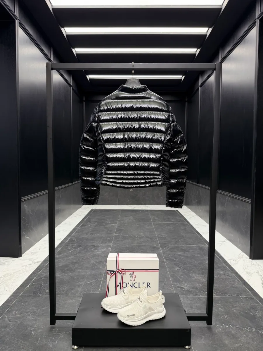 Чёрный пуховик Moncler на стойке в интерьере, вид со спины