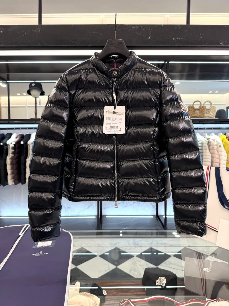 Чёрный укороченный пуховик Moncler на вешалке над стеклянным столом