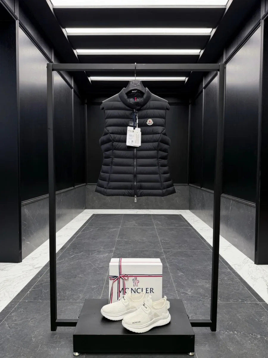 Чёрный стеганый жилет Moncler на вешалке в интерьере бутика, общий вид