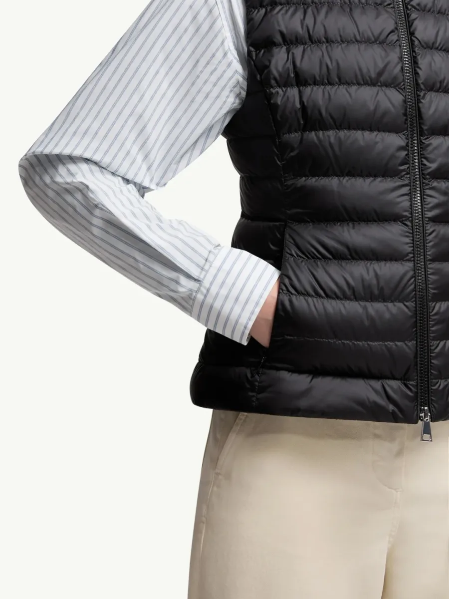 Боковой ракурс чёрного жилета Moncler на модели с рукой в кармане
