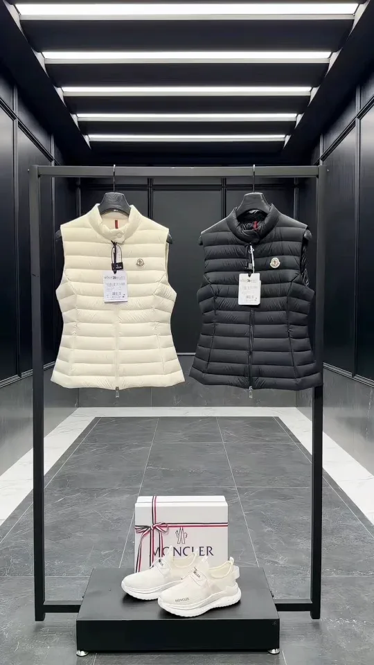 Чёрный и белый стеганые жилеты Moncler на вешалке в торговом зале