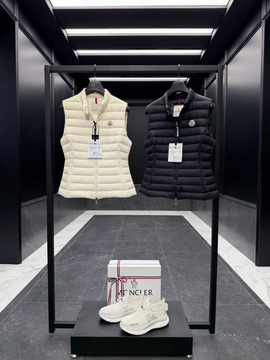 Два пуховых жилета Moncler чёрного и молочно-белого цветов на вешалке