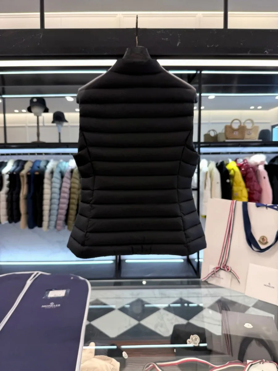 Вид со спины чёрного стеганого пухового жилета Moncler на вешалке