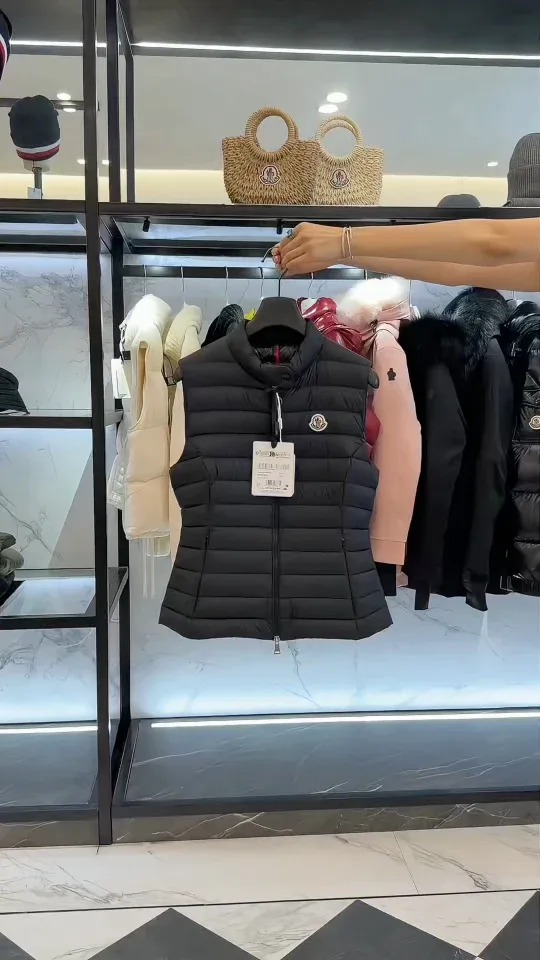Чёрный пуховый жилет Moncler на вешалке в руке консультанта