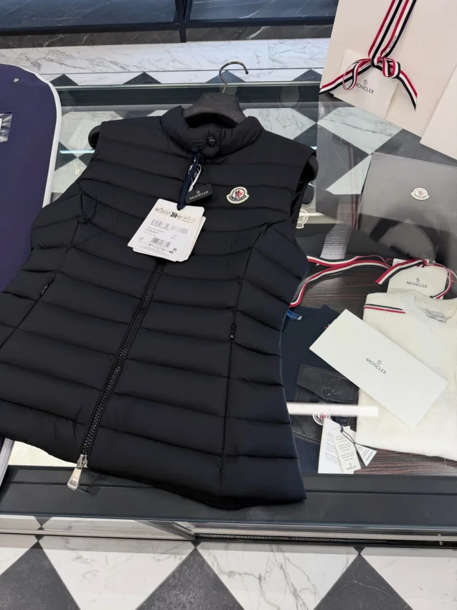 Чёрный пуховый жилет Moncler с воротником-стойкой и бирками сверху