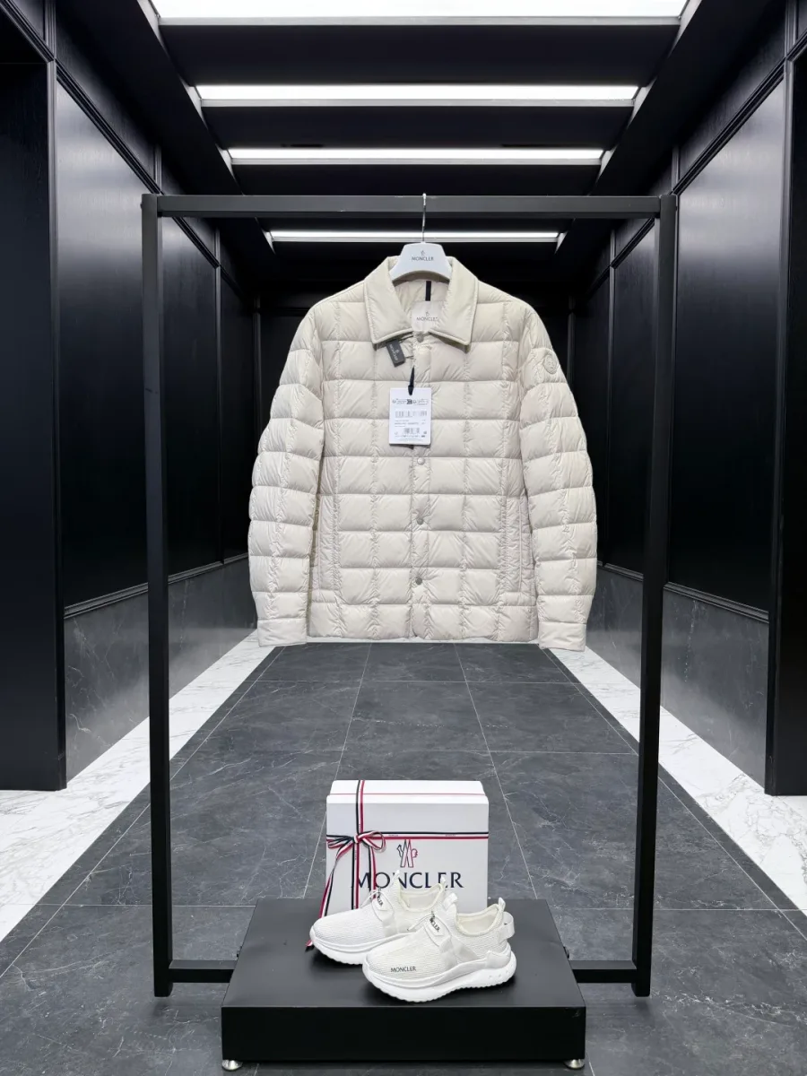 Светло-бежевый пуховик Moncler Castellane на вешалке на фоне обувной коробки, общий план