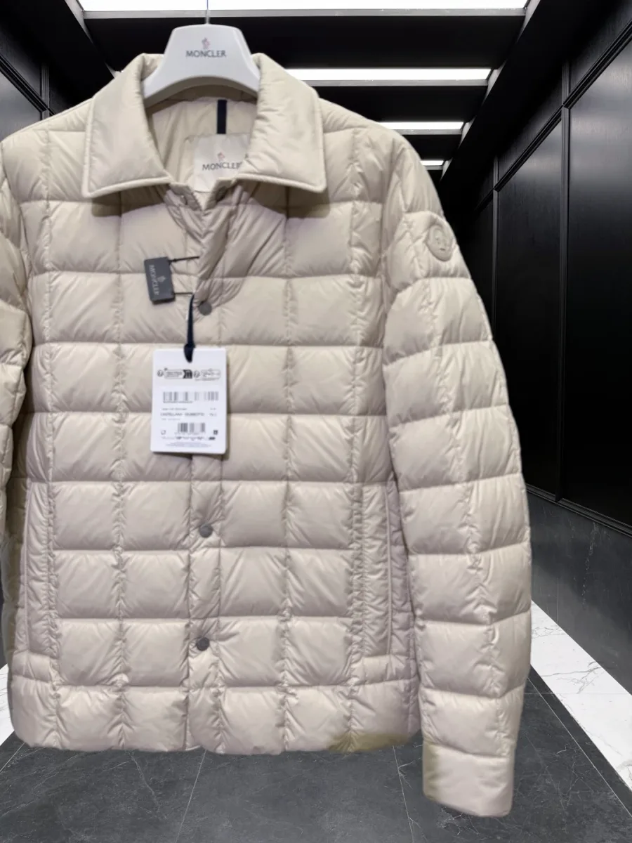 Пуховик Moncler Castellane бежевого оттенка с бирками на вешалке в полуанфас