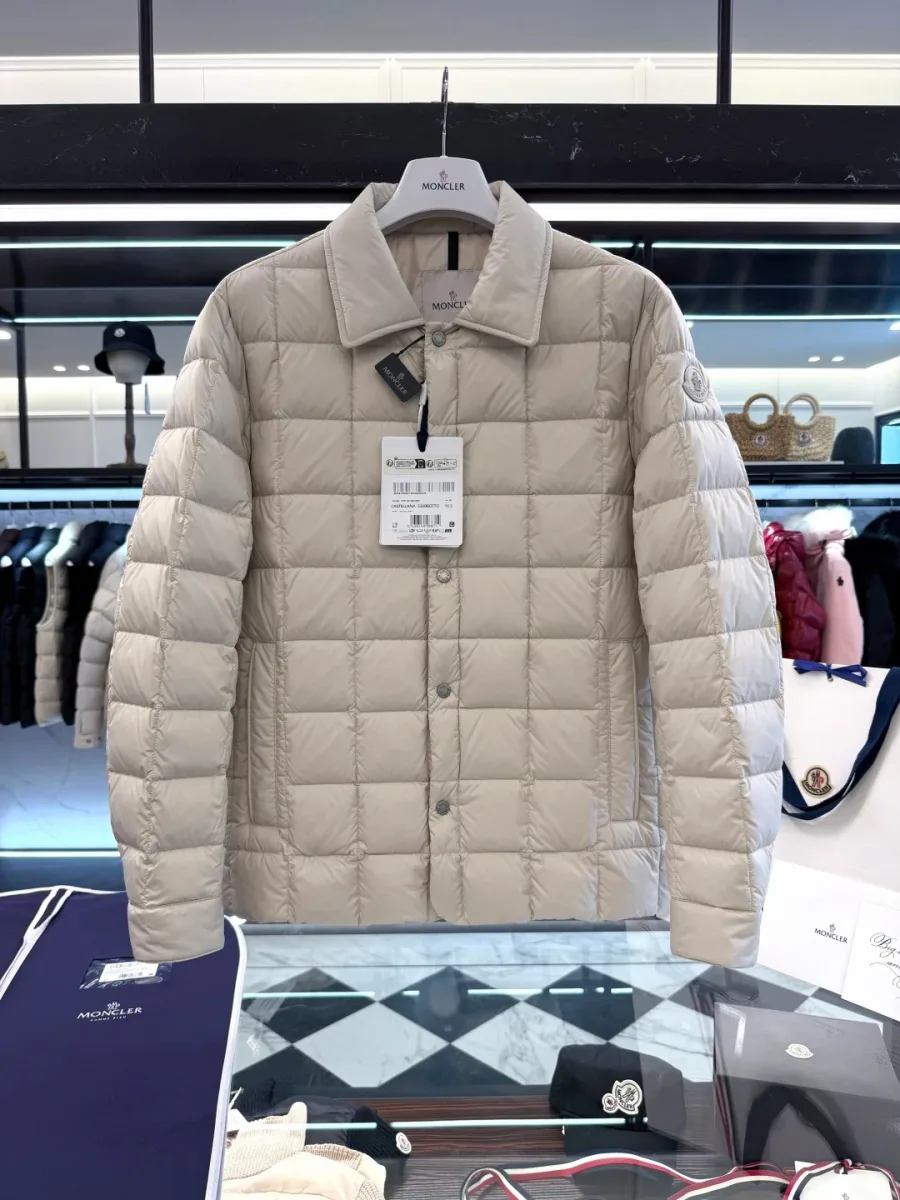 Бежевый пуховик Moncler Castellane на вешалке в торговом зале, фронтальный план