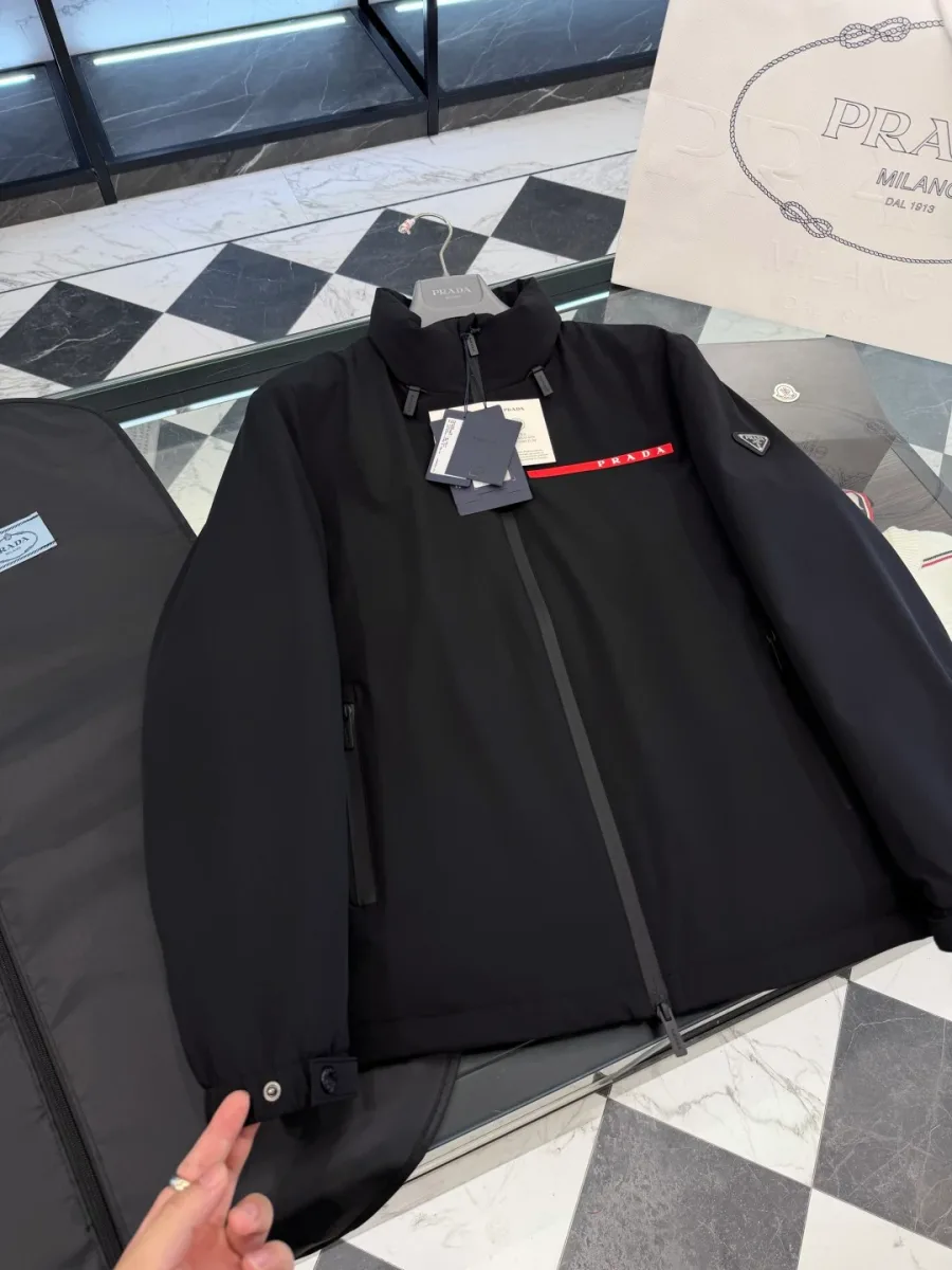 Крупный план рукава и передней части чёрной куртки Prada: манжета с кнопками и прорезной карман