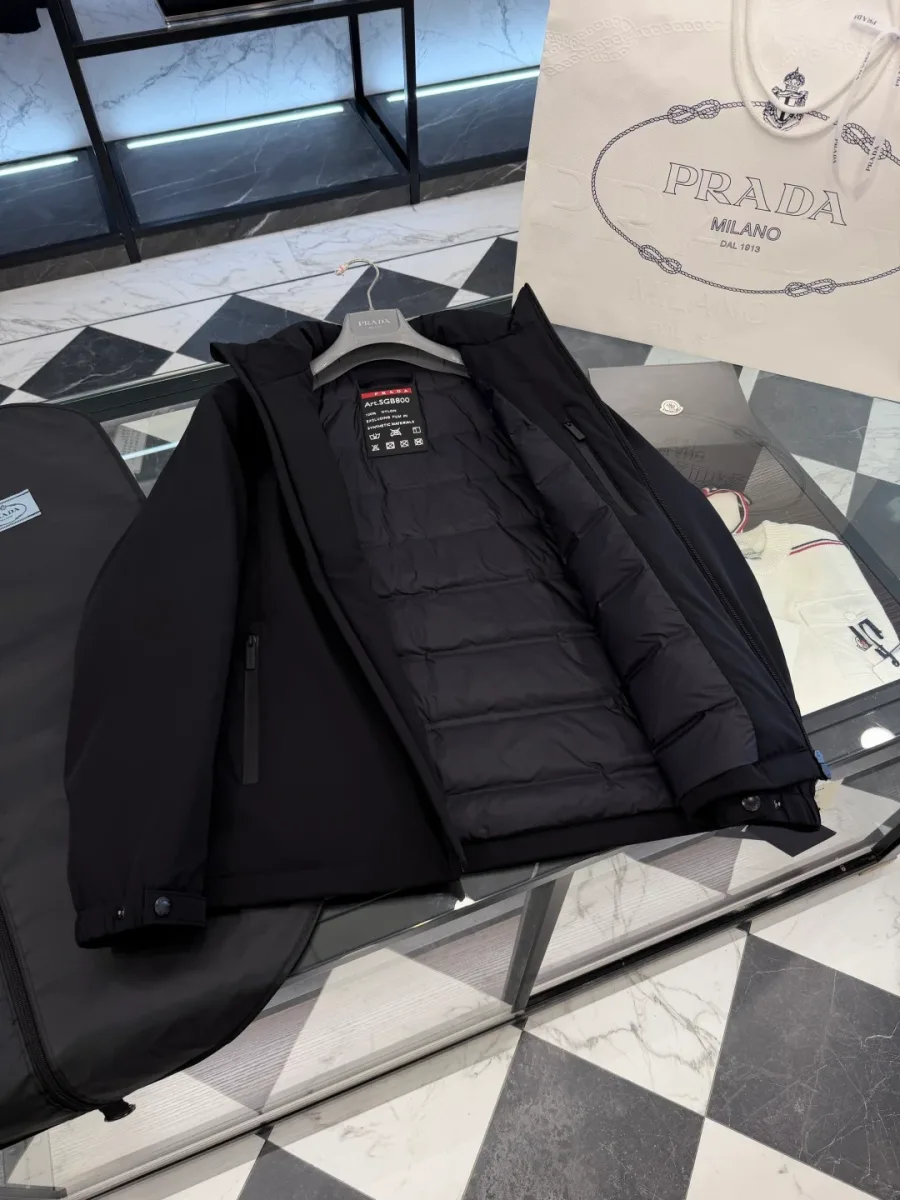 Внутренняя часть чёрной куртки Prada в раскрытом виде: камерная стёжка подкладки и нашивка у горловины