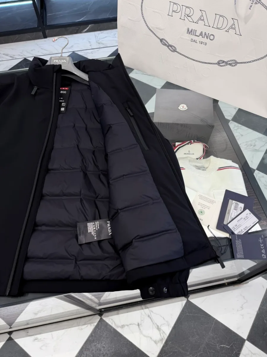 Детали изнанки чёрной куртки Prada: горизонтальные стёганые секции, внутренний карман и тканевые бирки