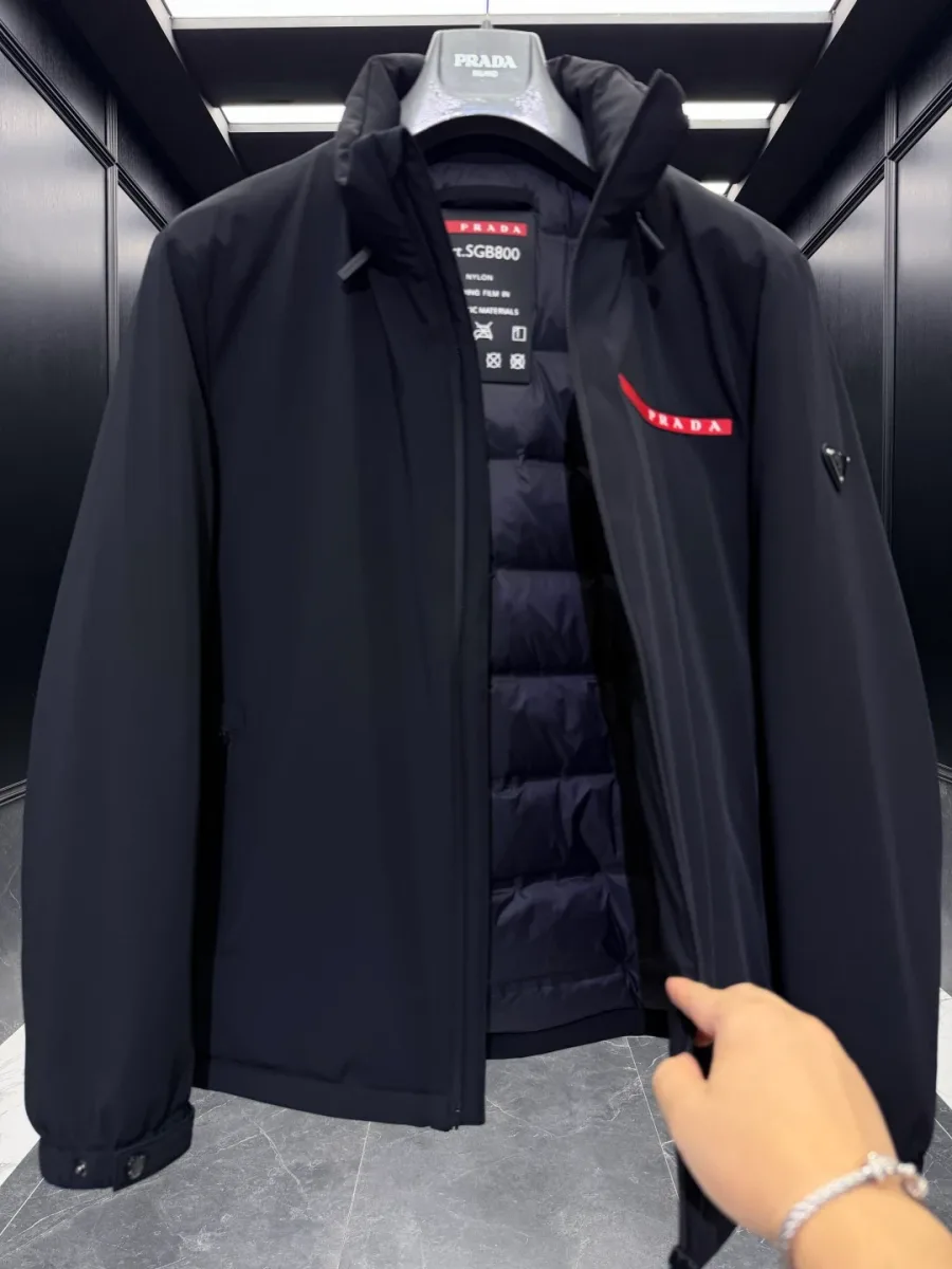 Чёрная куртка Prada в расстёгнутом виде: внутренняя горизонтальная стёганая подкладка и бирка у ворота