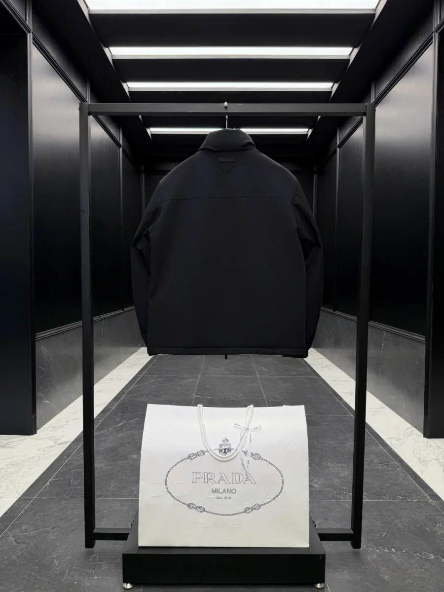 Чёрная куртка Prada Linea Rossa на рейле, вид со спины, гладкая матовая поверхность и прямой крой