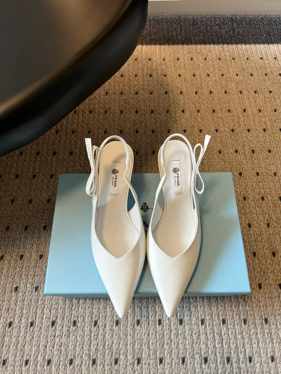 Белые слингбэки из лакированной кожи на каблуке, вид сверху на коробке Prada
