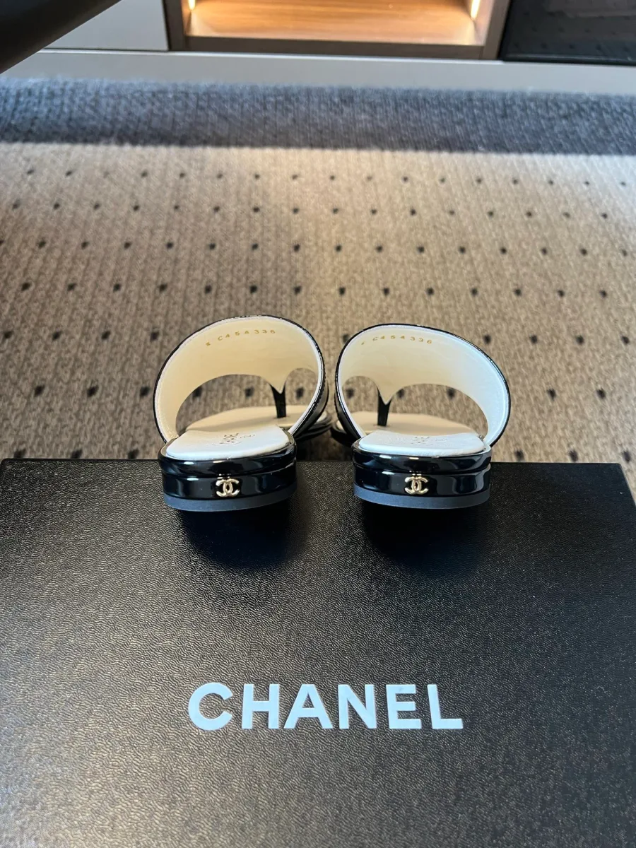 Задняя часть шлепанцев Chanel с декором на каблуке на фоне коробки