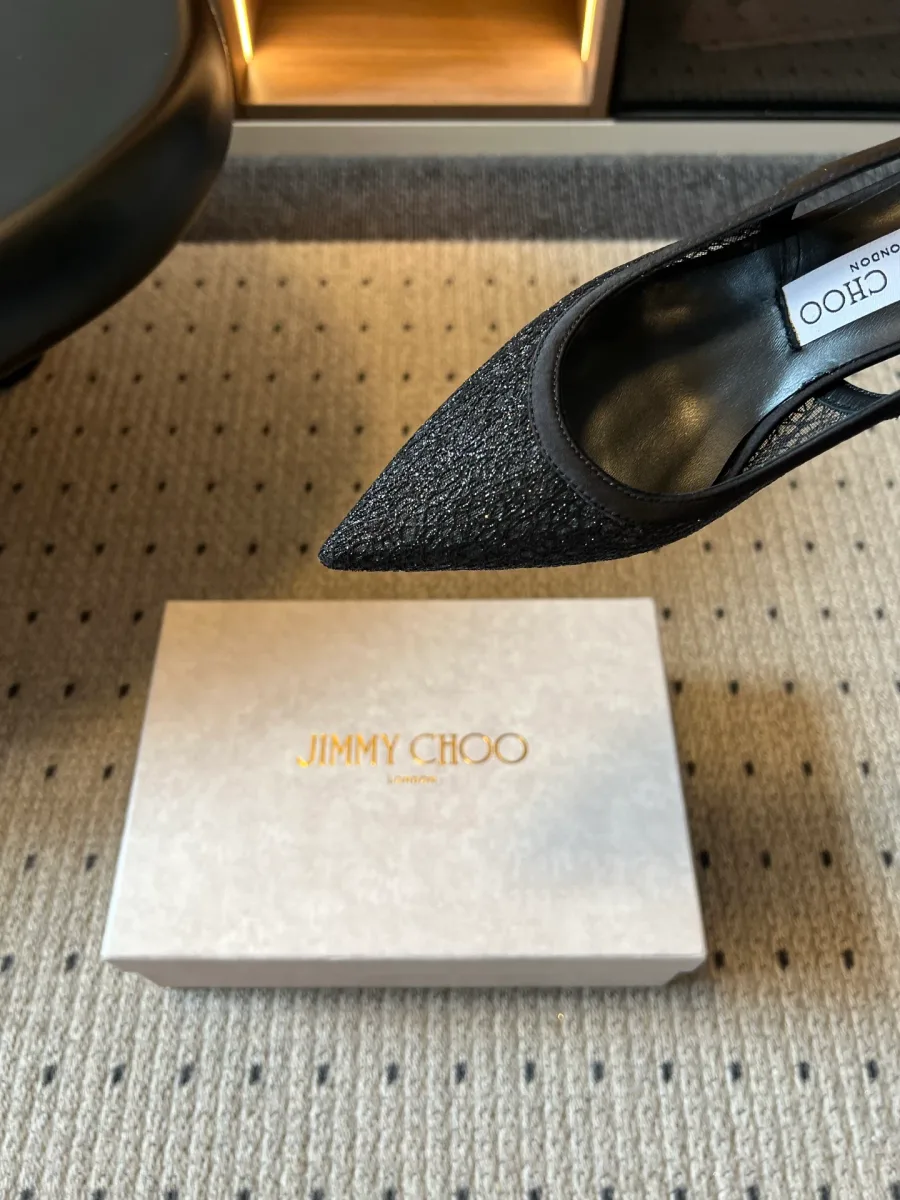 Крупный план острого кружевного мыса и выреза чёрной туфли Jimmy Choo