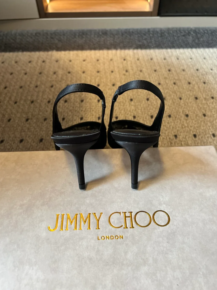 Вид сзади на тонкие каблуки и пяточные ремешки чёрных туфель Jimmy Choo